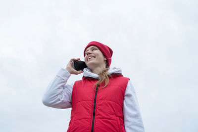 Woman wearing knee brace or orthosis after leg surgery walking in the park using smartphone