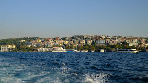 Buildings by sea against clear sky