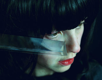 Close-up of woman with glass in darkroom