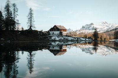 Reflection of houses and trees in lake against sky