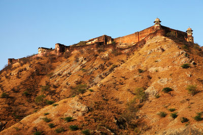 Low angle view of amer fort on mountain against clear sky