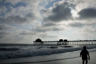 Silhouette man standing on beach against sky