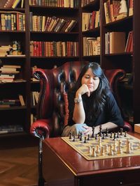 Full length of young woman sitting playing chess