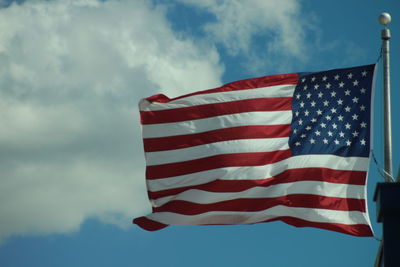 Low angle view of american flag waving against cloudy sky