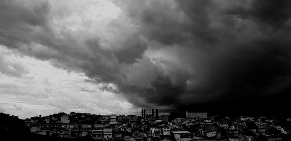 Buildings in city against storm clouds