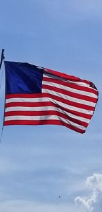 Low angle view of american flag against blue sky