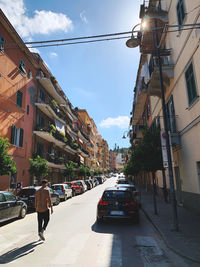 Cars on street amidst buildings in city against sky