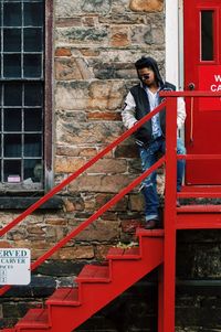 Full length of woman sitting on wall