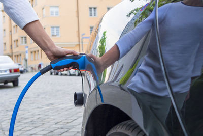 Man charging electric car on street in city