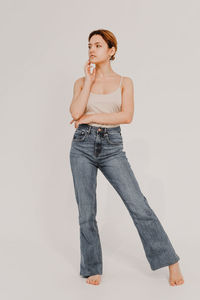Portrait of young woman standing against white background