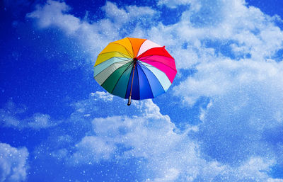 Low angle view of umbrella flying against sky