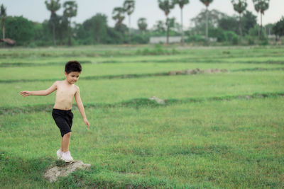 Full length of shirtless man standing on field