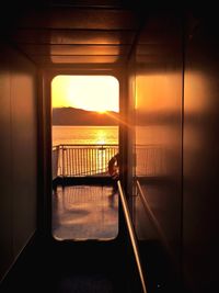 View of sea through window at sunset