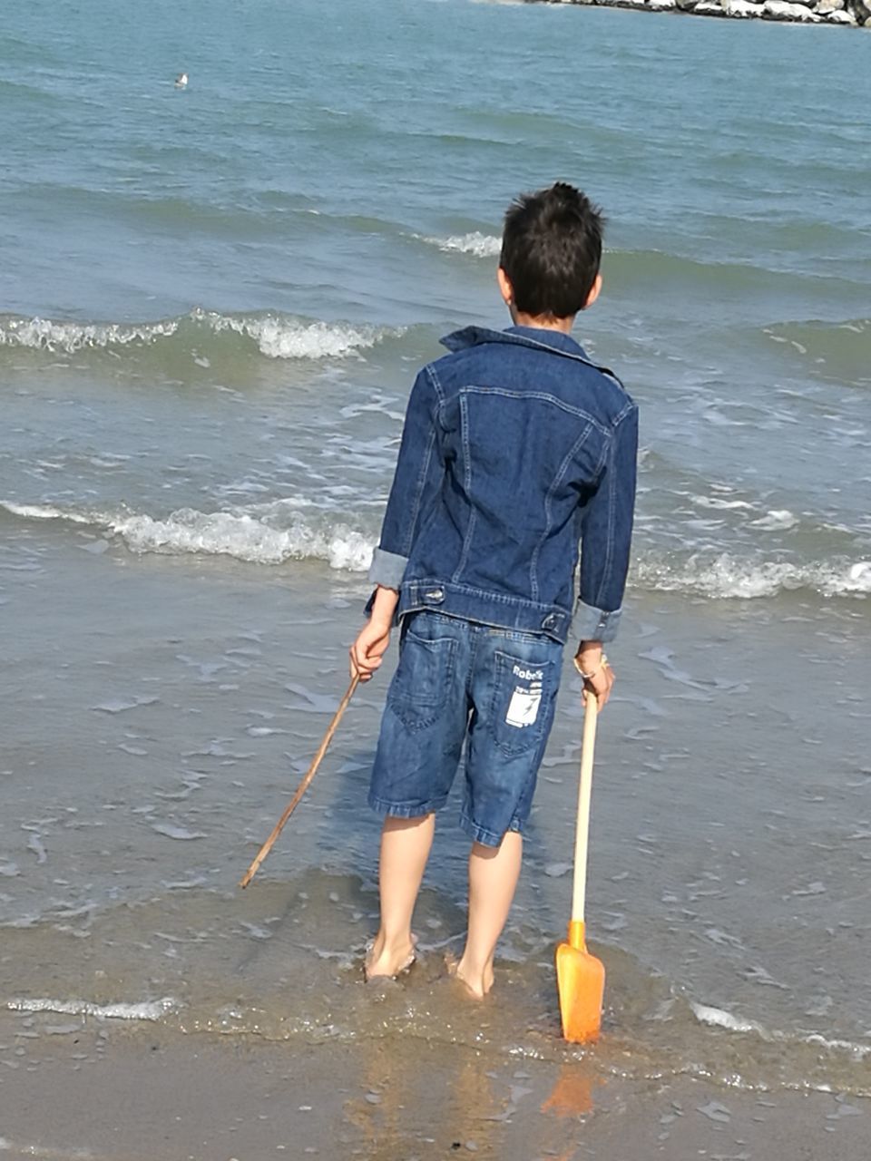 FULL LENGTH REAR VIEW OF A MAN STANDING AT BEACH