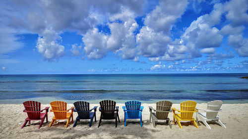 Chairs on beach against blue sky