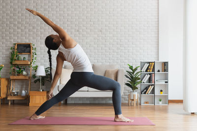 Full length of woman with arms raised on floor