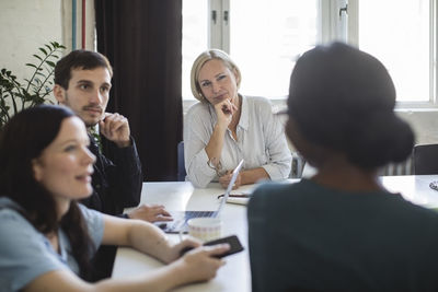 Entrepreneurs listening to female colleague during meeting in board room