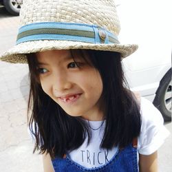 Close-up of happy girl wearing bucket hat while standing by car