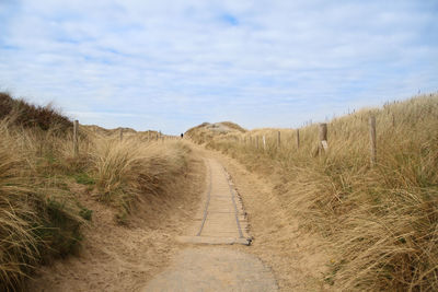 Dirt road along landscape against sky