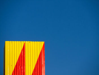 Close-up of multi colored flag against blue sky