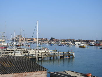 Sailboats in harbor by buildings against sky