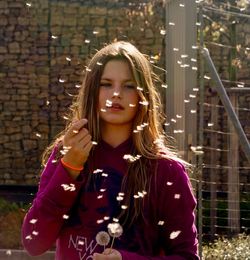 Teenage girl with dandelion seeds in mid-air