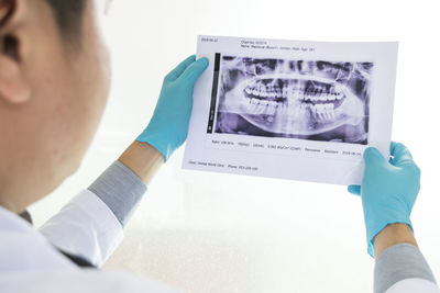 Close-up dentist examining x-ray image against white background