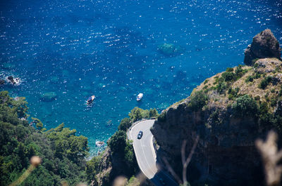 Amalfi coast - detail of hairpin bend, cliff, turquoise sea and boats. view from path of gods.