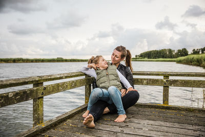 Mother and daughter on jetty at a lake