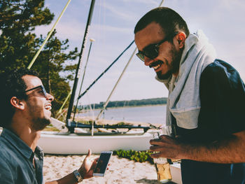 Cheerful friends talking at beach during summer