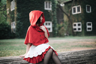 Rear view of woman with red umbrella standing against building