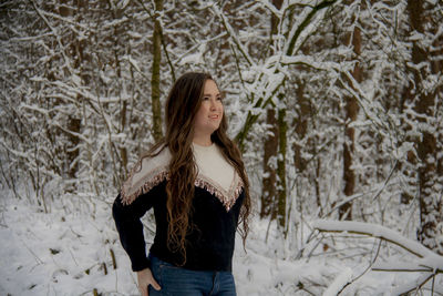 Young woman standing against trees