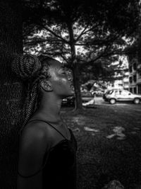 Portrait of young woman standing against trees