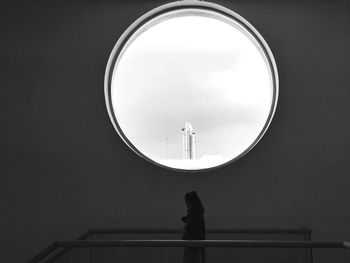 Rear view of woman standing by railing against sky
