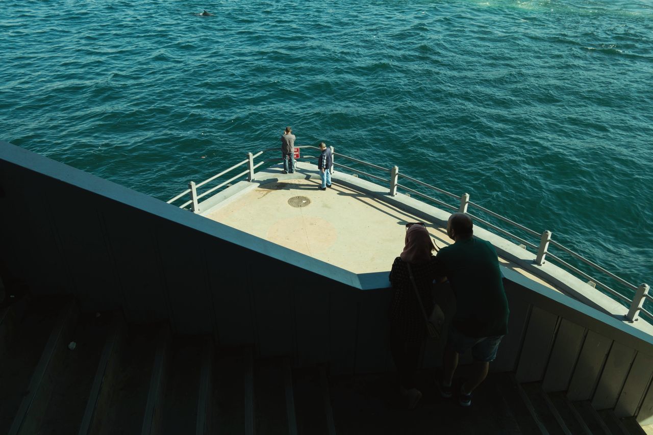 high angle view, adults only, sea, real people, railing, lifestyles, only men, men, large group of people, outdoors, adult, people, water, young adult, day, boat deck