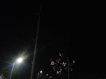 Low angle view of illuminated street lights against clear sky at night