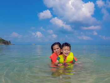 Mother and son in sea against sky