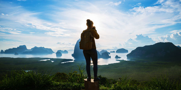 Rear view of woman standing on mountain against sky