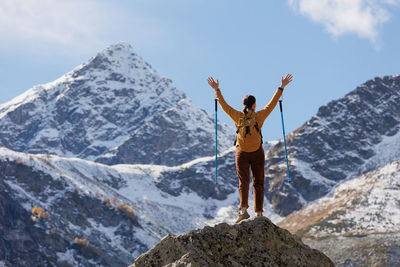 Rear view of man standing on mountain against sky