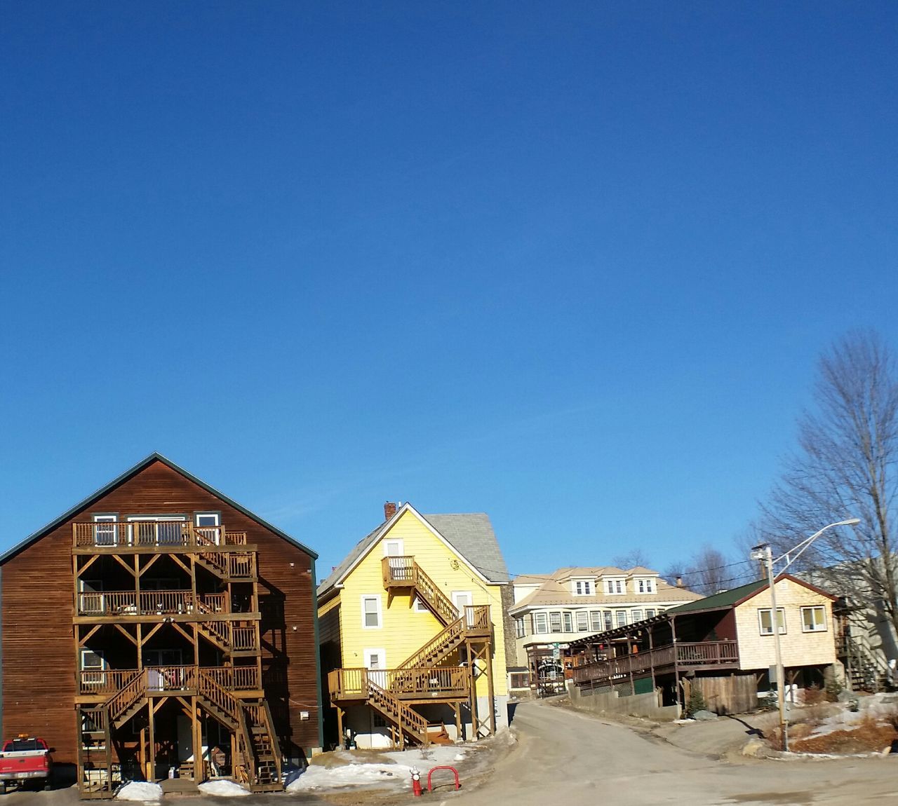 clear sky, building exterior, architecture, built structure, blue, copy space, house, residential structure, residential building, street, car, road, sunlight, snow, day, outdoors, winter, town, cold temperature, transportation