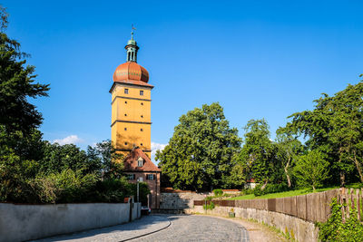 Tower amidst trees and buildings against clear blue sky