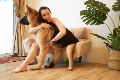 Portrait of young woman with dog on hardwood floor