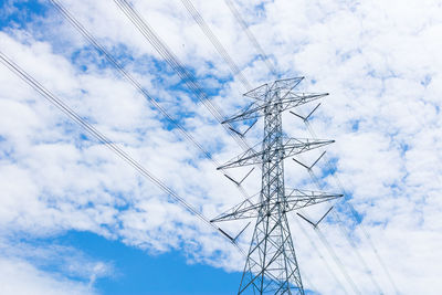 Low angle view of electricity pylon against cloudy sky