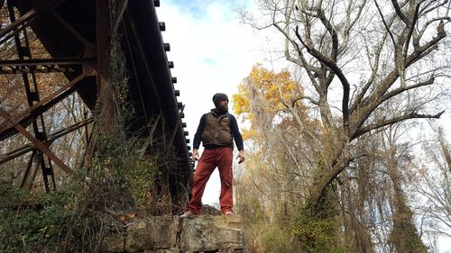 Rear view of woman walking on built structure against trees