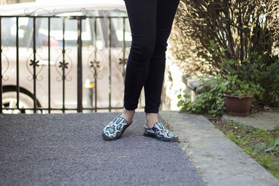 Low section of woman standing on footpath