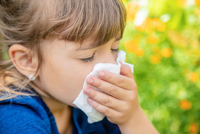 Sick girl having allergy wiping nose