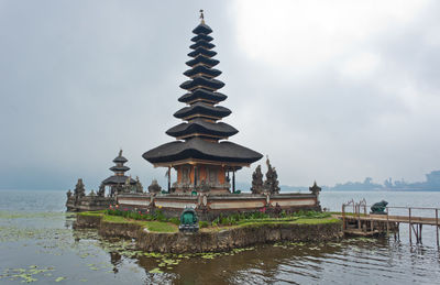 View of building by lake against sky