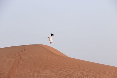 Man on sand dune against clear sky