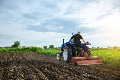 A farmer on a tractor grinds the soil before planting a new crop. work on the plantation