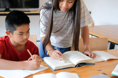 Boy girl student studying writing notes doing homework in library. learning education at school